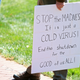 A man holding a sign incorrectly insisting the pandemic is just cold season in Virginia, April 16.